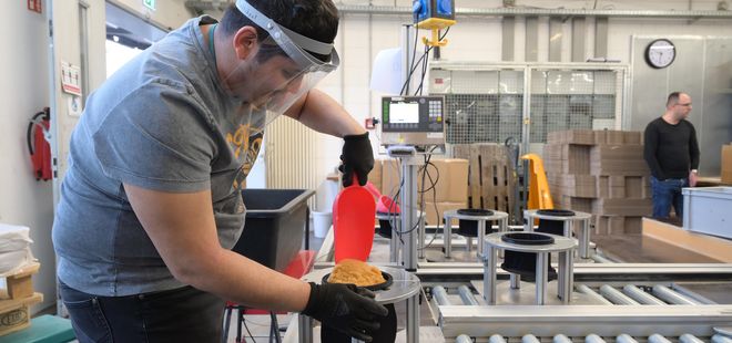 Mann füllt Produkt in Säcke ab