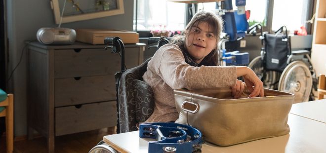 eine Frau im Rollstuhl sitzt am Tisch